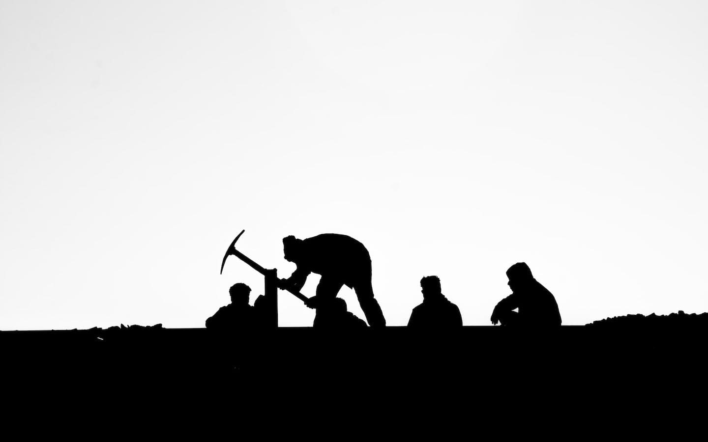 A silhouette of several people working outside.