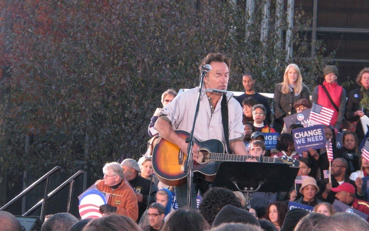 Bruce Springsteen performing on stage with an acoustic guitar.