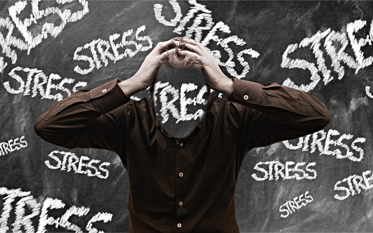 Guy with hands on head and words stress all around him