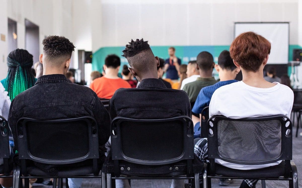 Students sitting in a classroom photographed from the back of the room.
