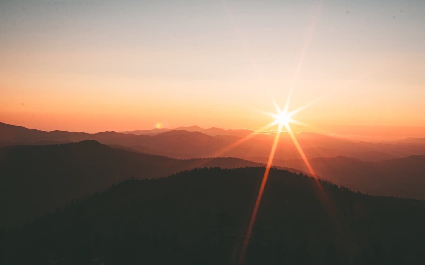The sun rising over mountains.