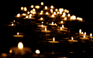 Multiple tea light candles lighting up a dark room.
