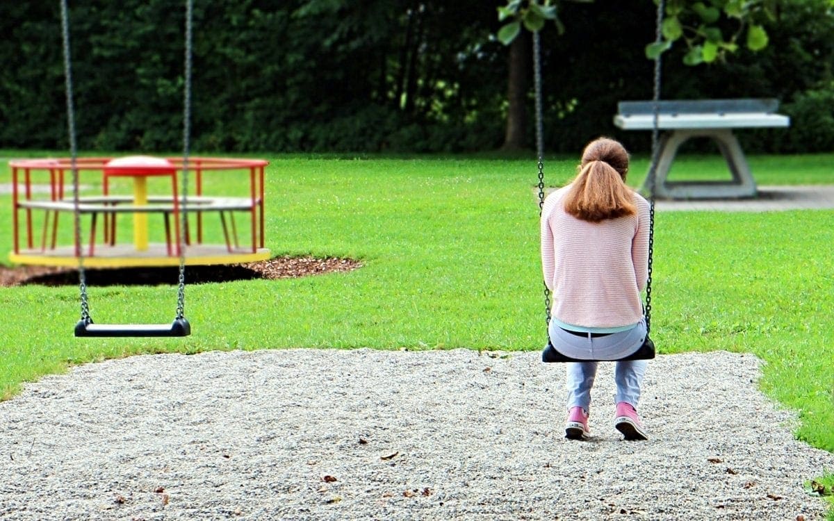 Older teen girl on playground swing