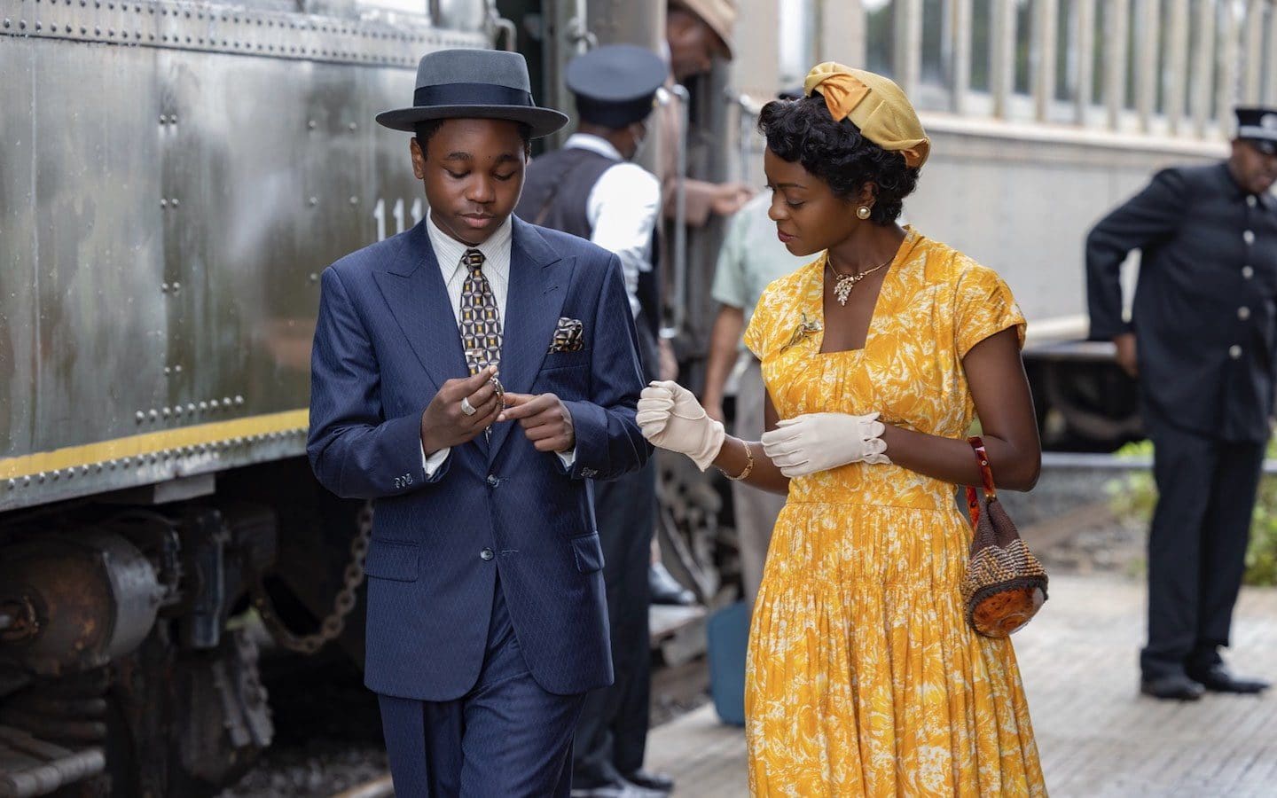 A press release photo for the movie “Till” featuring a man and woman walking on a sidewalk next to a train.