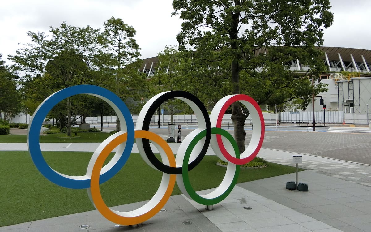 The Olympic Rings in front of the Japan Olympic Museum with Japan National Stadium in the background.
