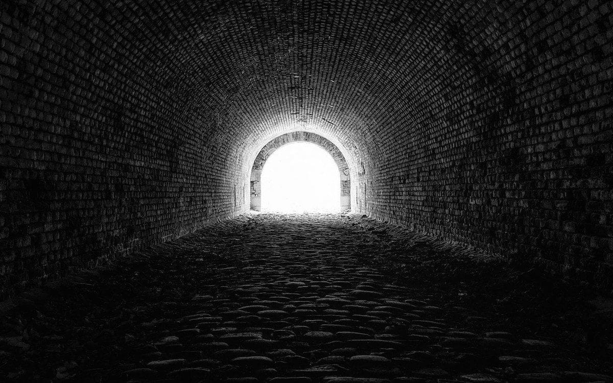 A dark tunnel looking toward the light at the end.