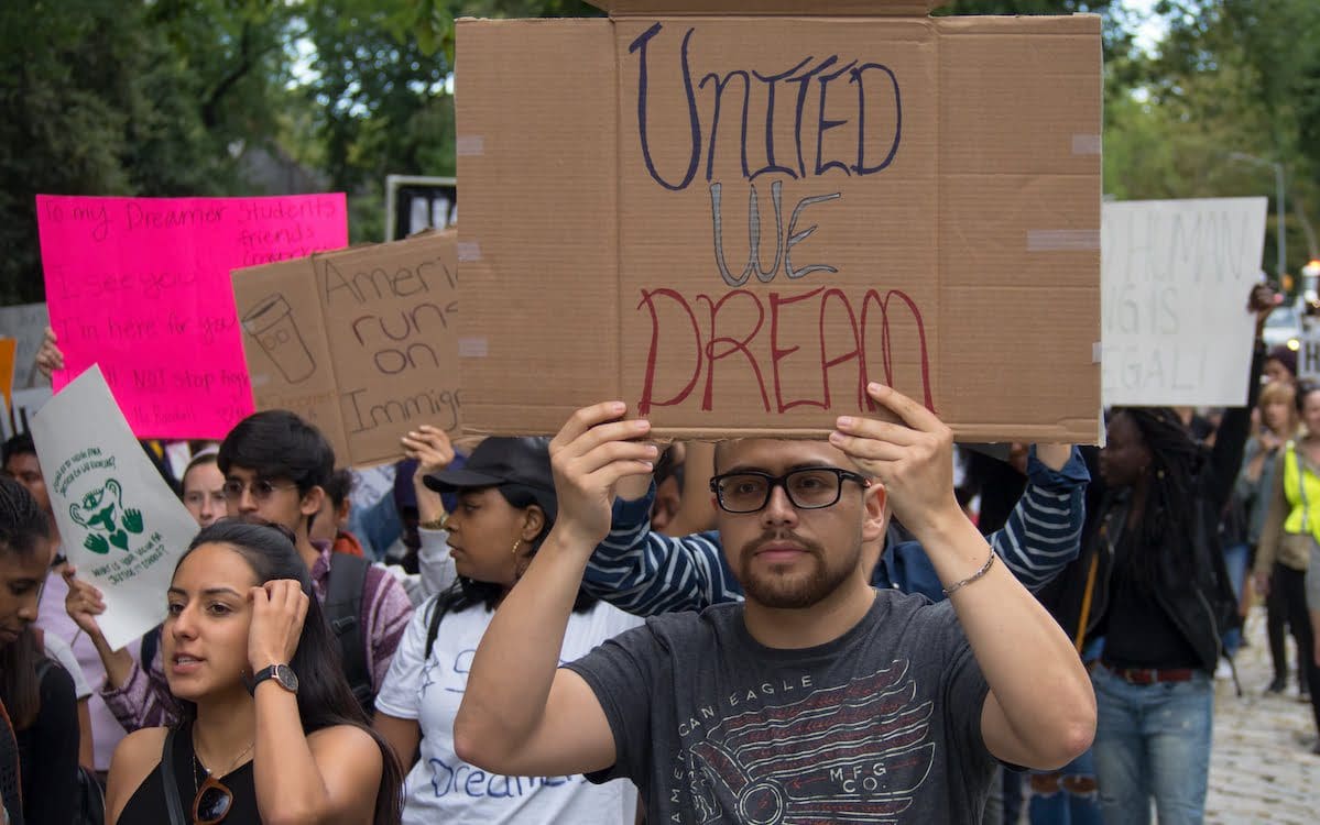 People at a march to support the DACA program with one man holding a sign that says