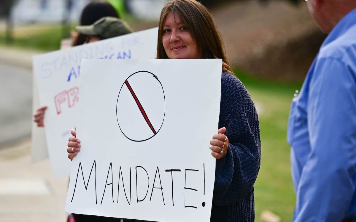 A woman at a protest holding a sign protesting vaccine mandates.