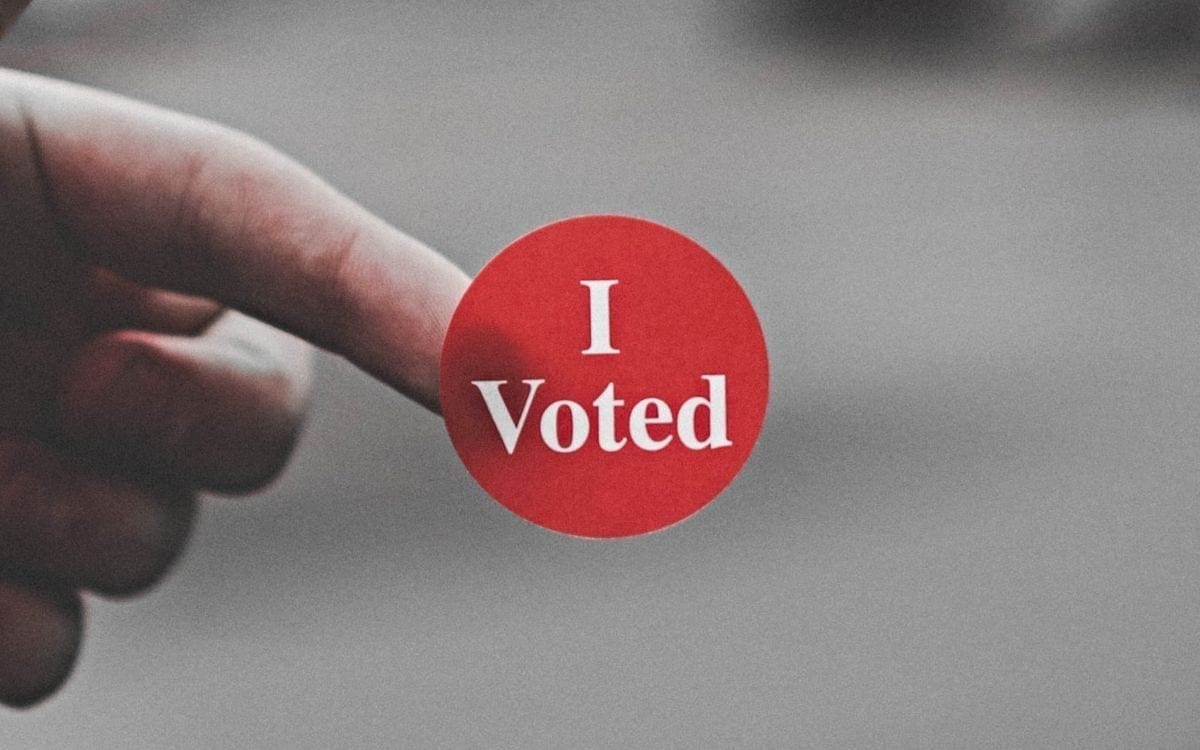 Finger with I Voted sticker on its tip