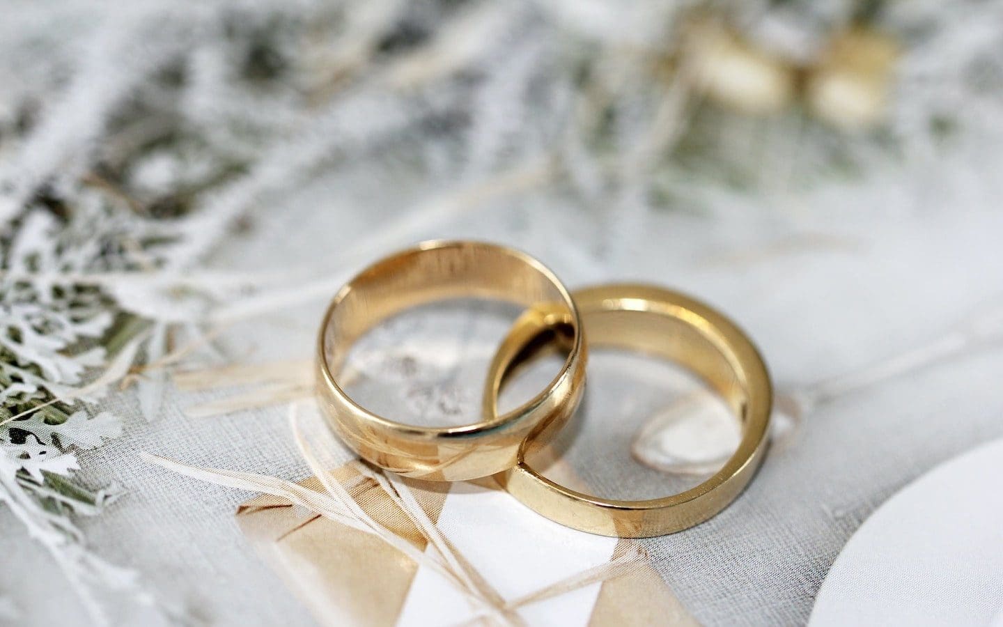 A pair of gold rings on top of white linen.