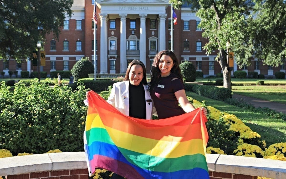 Two women holding LGBTQ flag at Baylor
