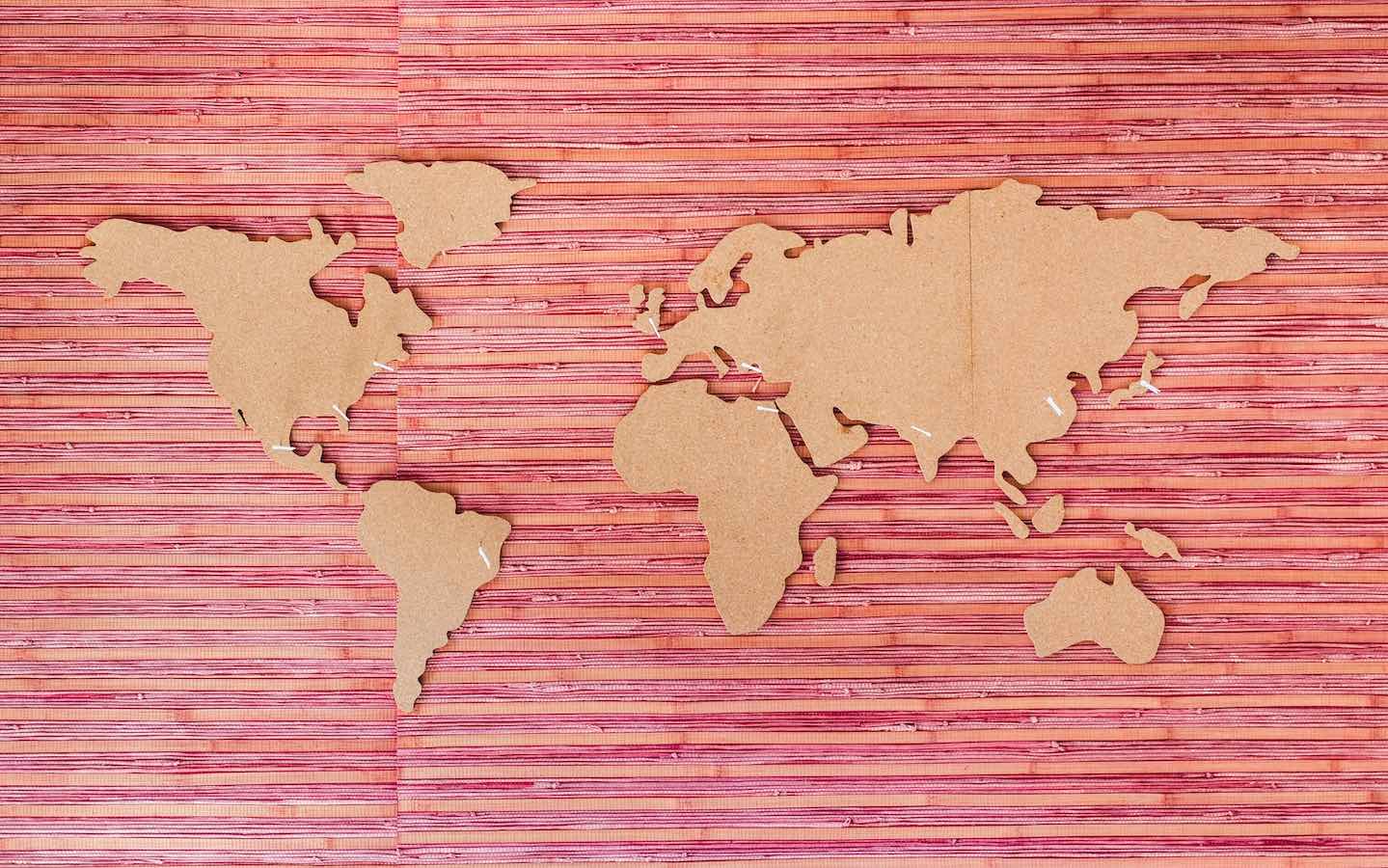 Outlines of the major continents in wood mounted on a red wall.