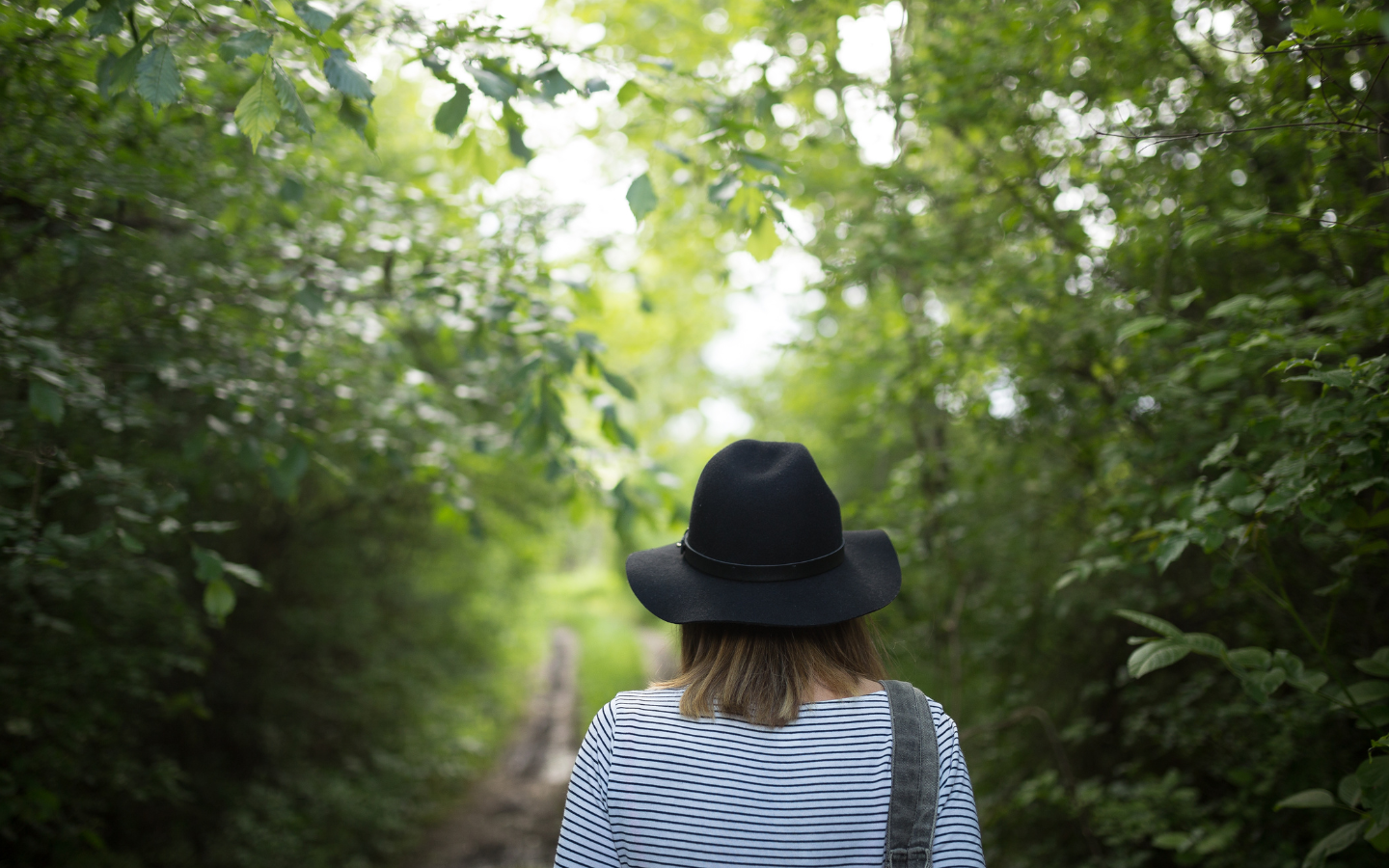 A woman walking along a pathway in the forest.
