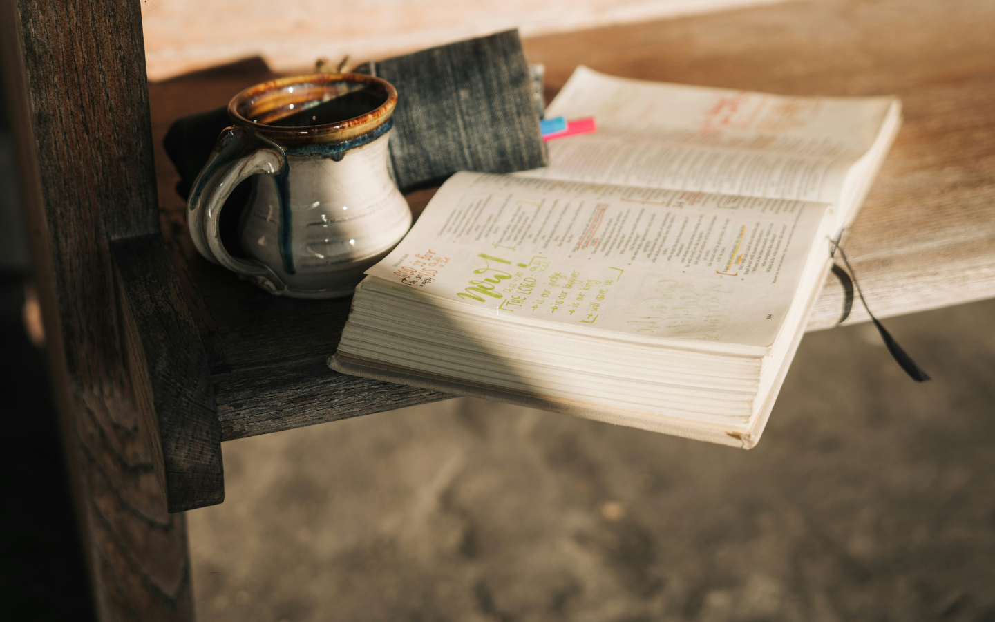 A cup of coffee and an open Bible on a church pew.
