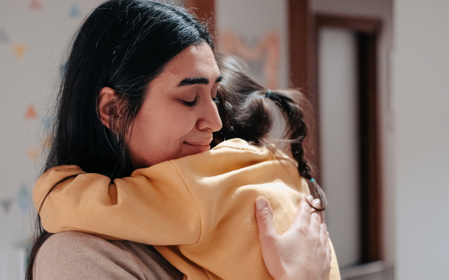 A young girl hugs her mother.