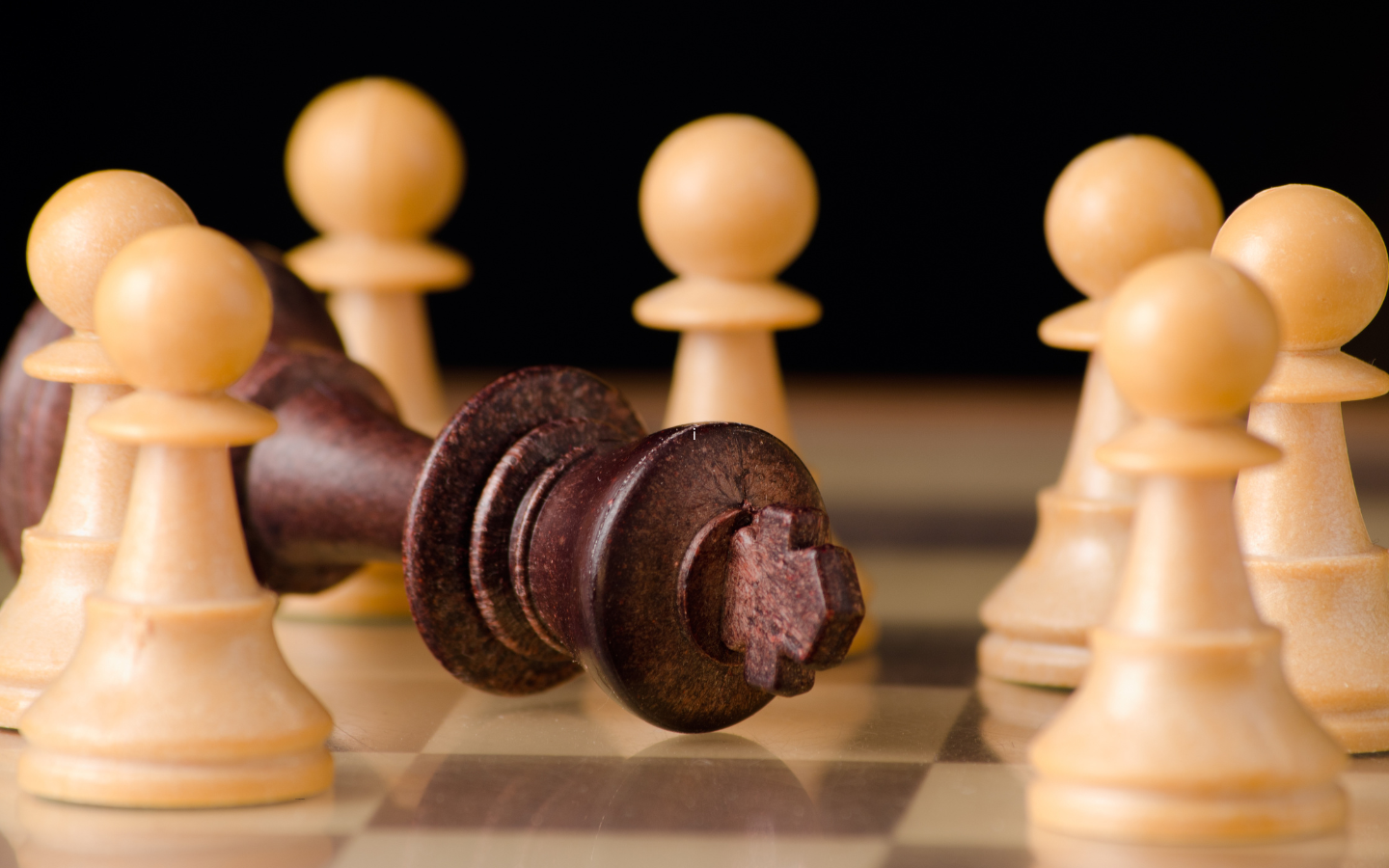 Pawns on a chess board surround a fallen king.