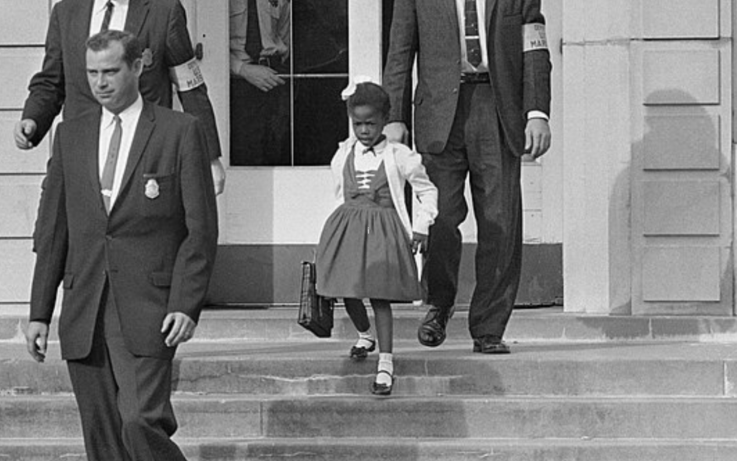 A photo of young Ruby Bridges being escorted to school by U.S. Marshals.