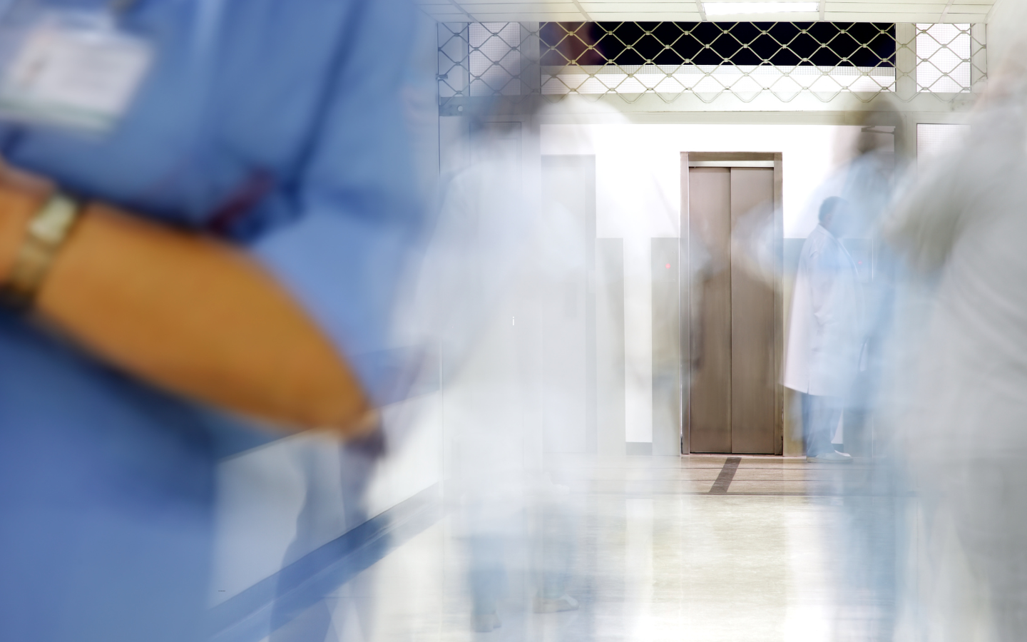 An image of a hospital corridor with blurred images of people walking around.
