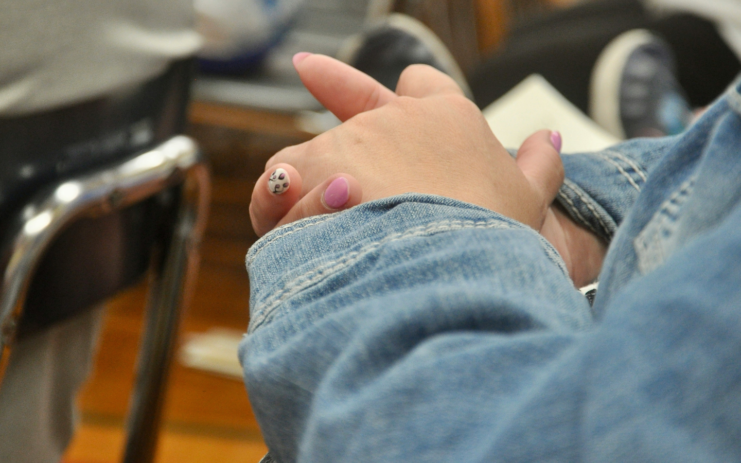 A close-up of hands with painted fingernails clasped in prayer in church.