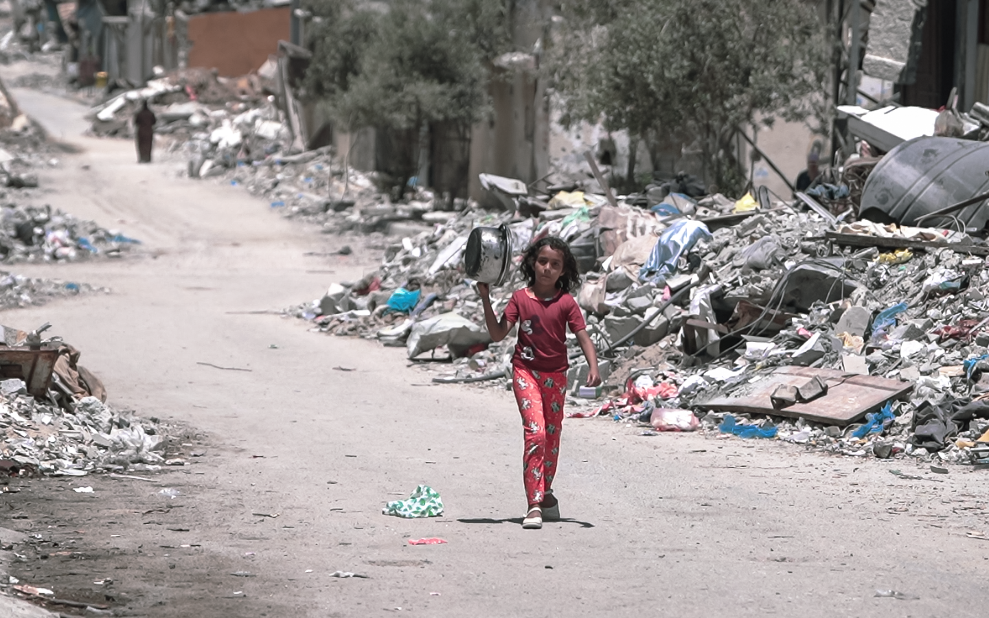 A girl walks along the rubble in Gaza in search of food.