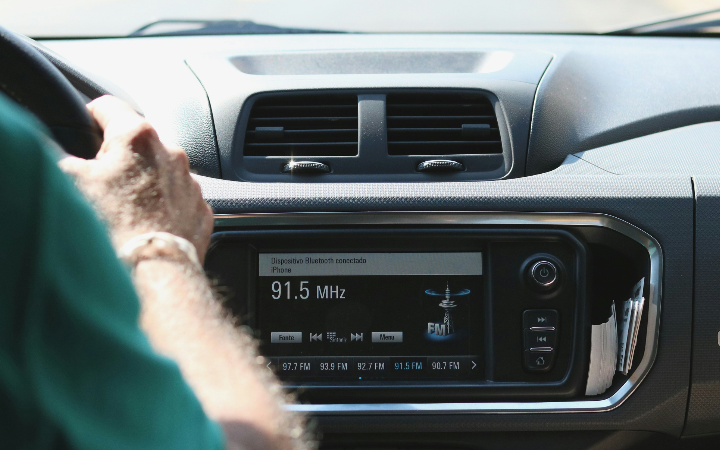 A man driving with a car radio playing.