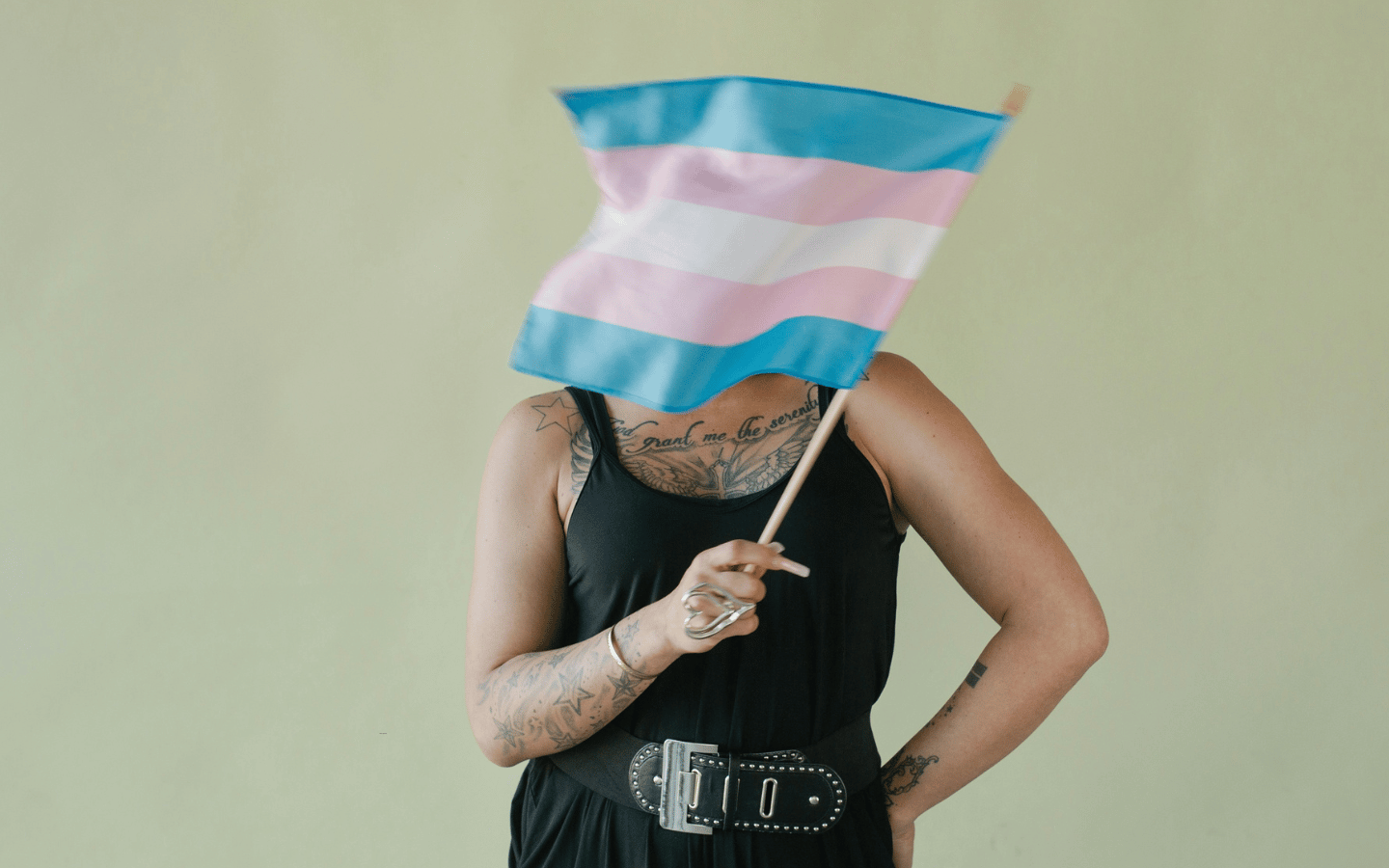 A person waves a Trans Flag in front of their face.