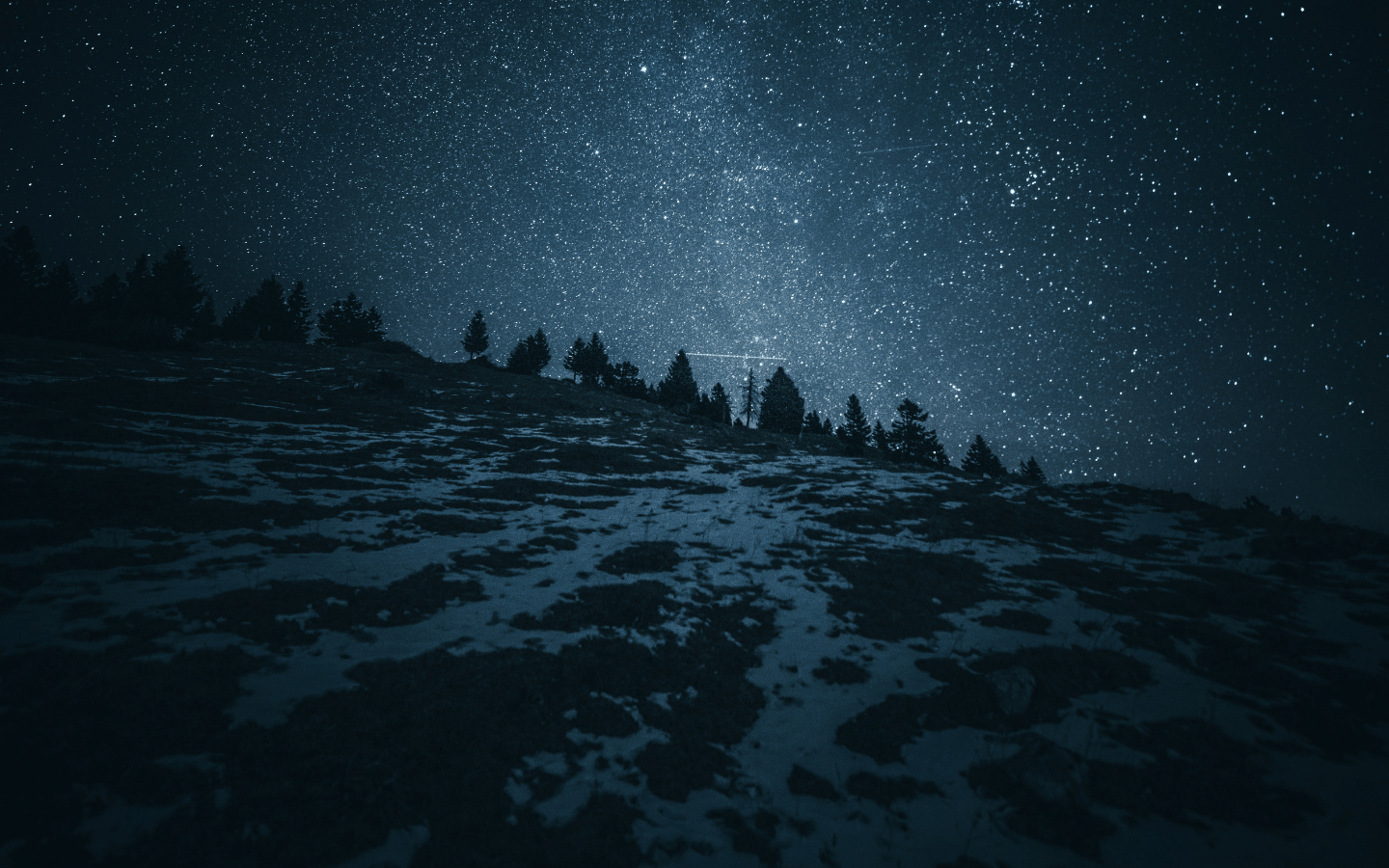 A snowy mountain at night, with stars visible.