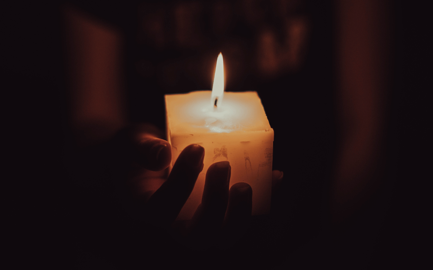 A person holds a candle in a dark room.