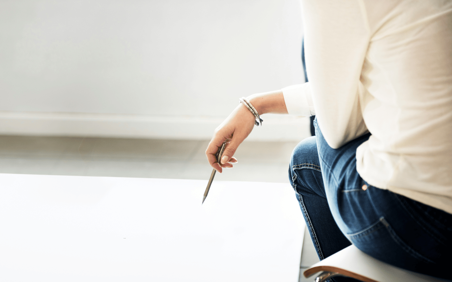 A woman sits confidently, with a pen in her hand.