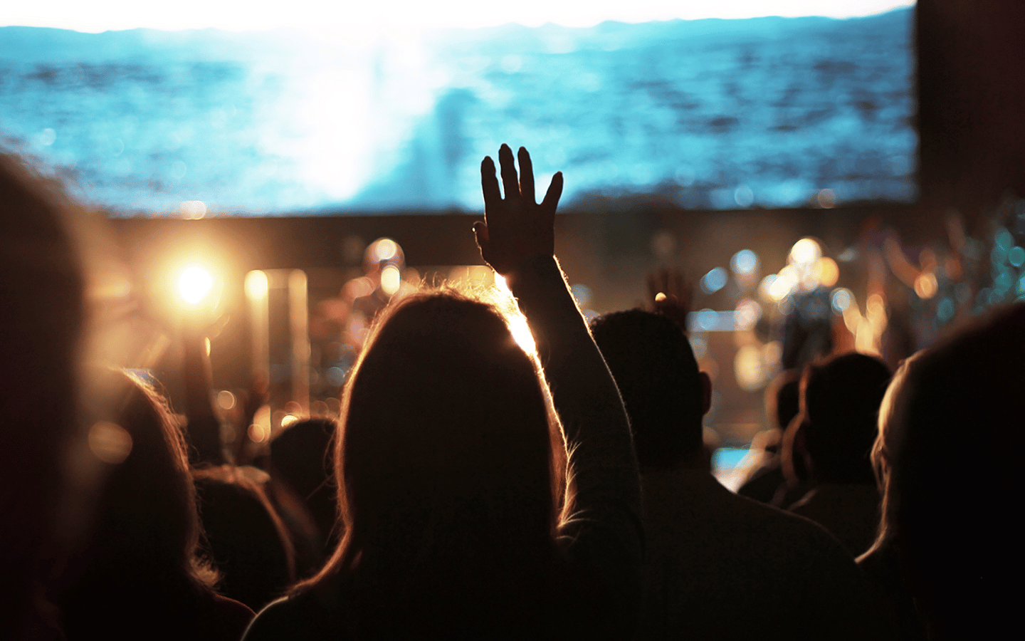 A person lifts her hands in worship at an evangelical megachurch.