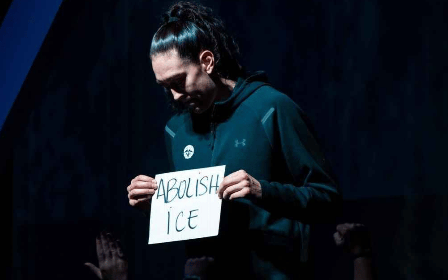 Breanna Stewart holds an “Abolish ICE” sign.