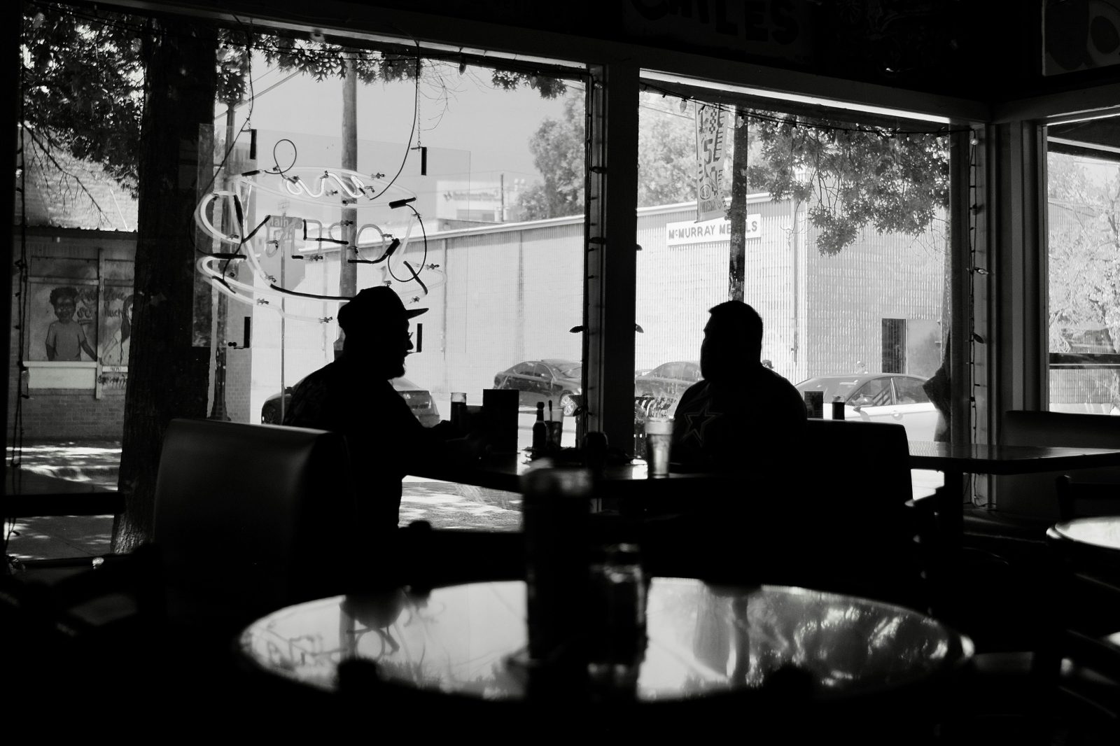 Two men have a conversation in a restaurant booth.