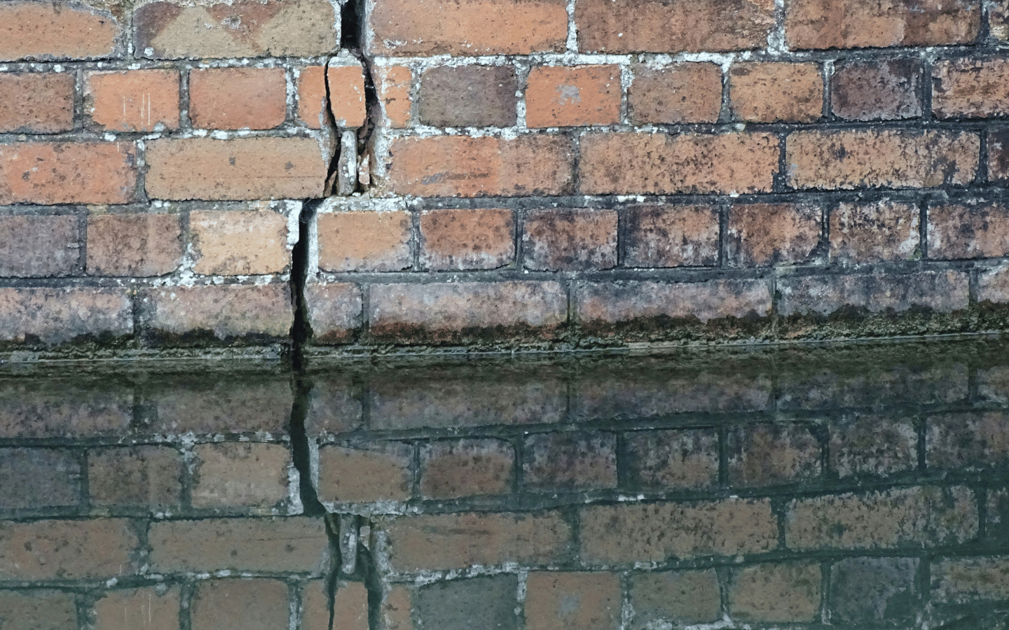 Cracks form in a brick wall.