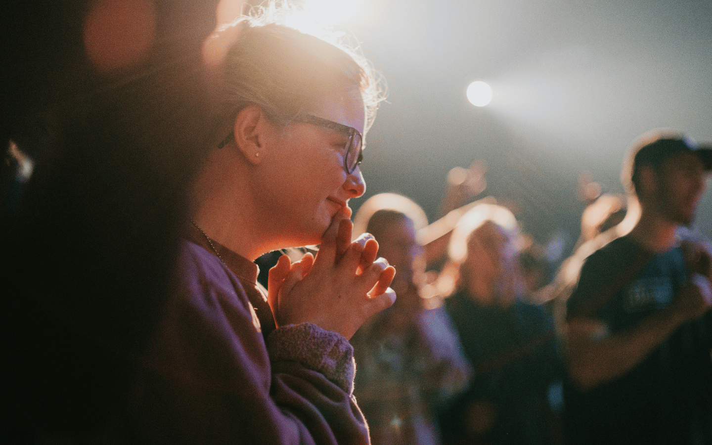A worship service with young people under canister lights.