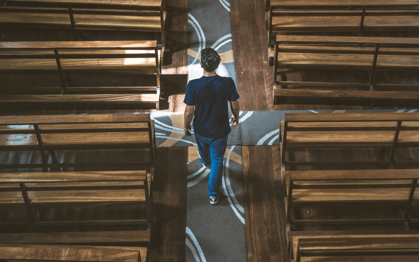A man walks the aisle of an empty church building.