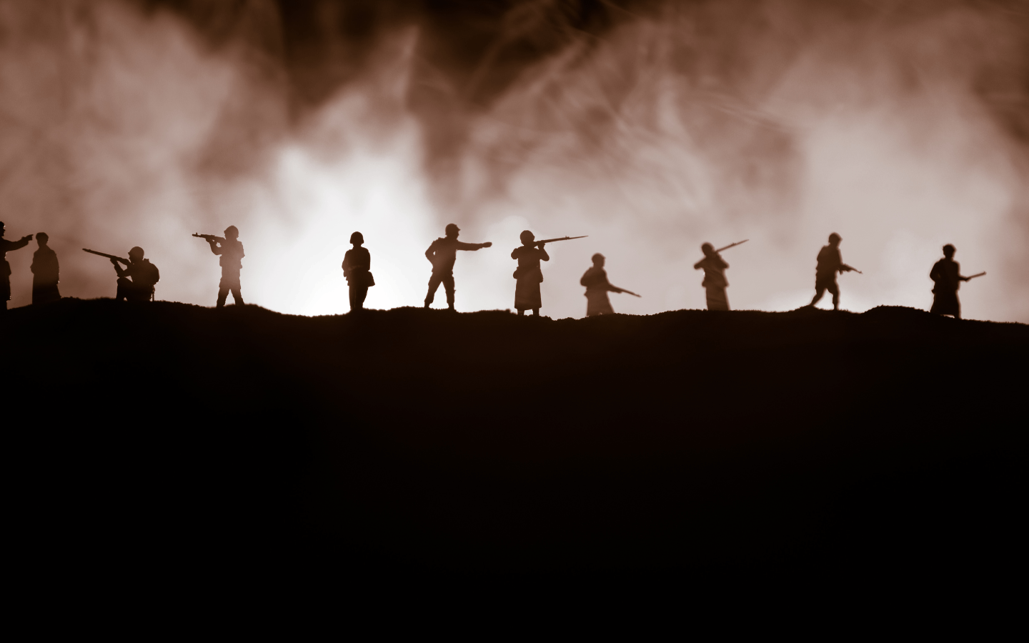 Silhouettes of soldiers on the horizon of a battlefield.