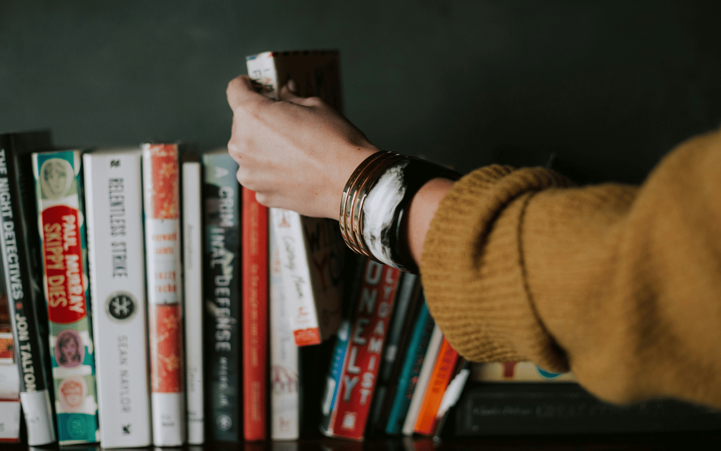 A woman chooses a book to read.
