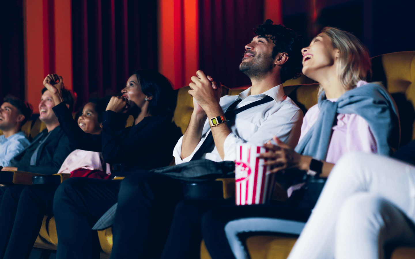 Various people enjoy a film at the theater.