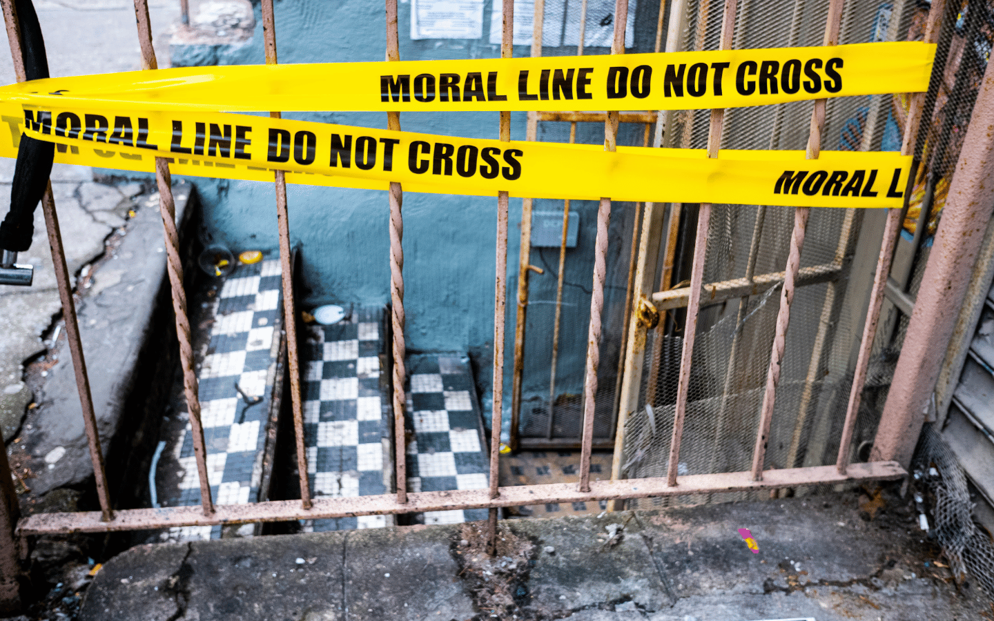 Police tape that reads, “Moral Line: Do Not Cross” leading down into a ramshackle building.