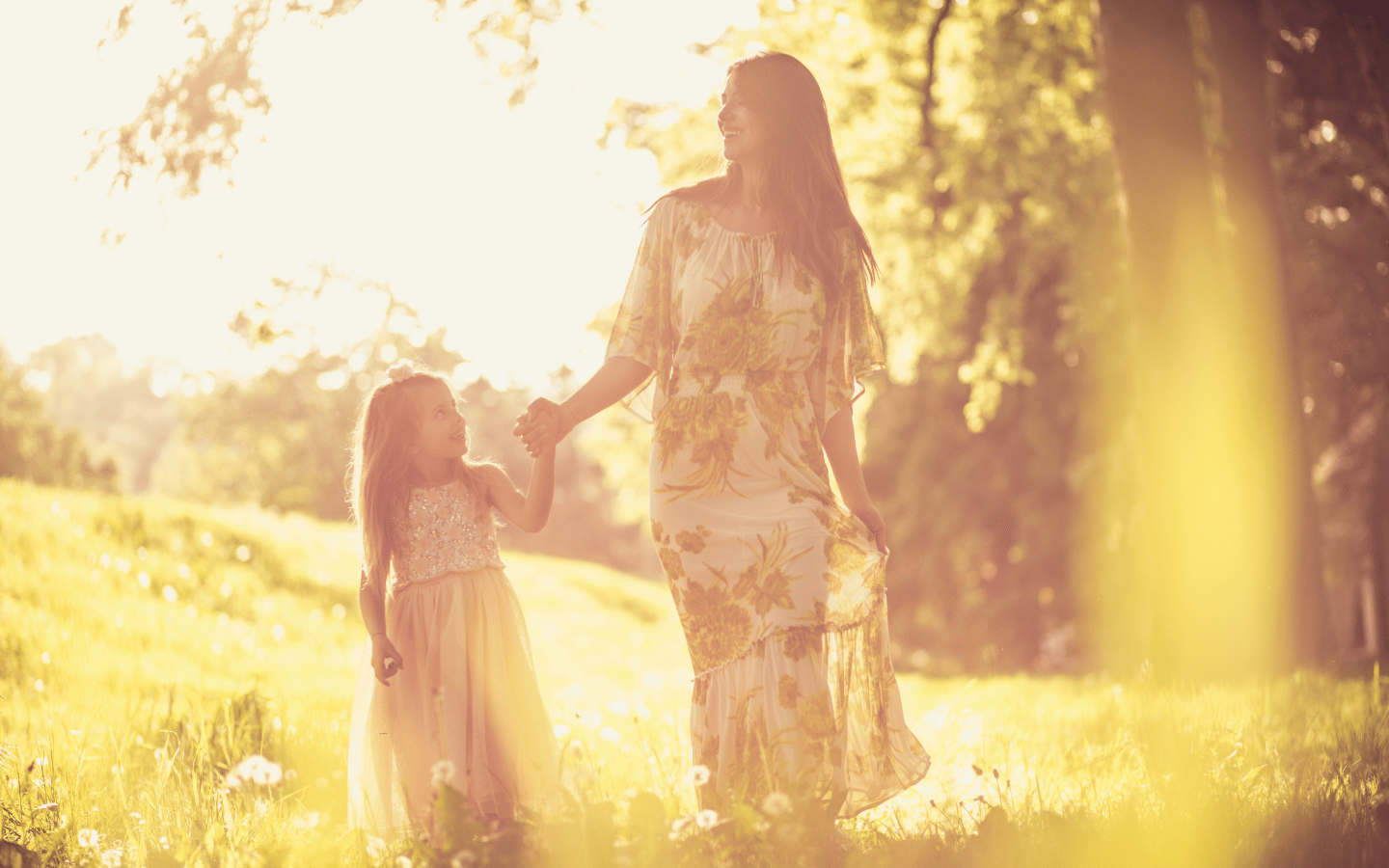 A sepia-filtered image of a mother walking through a forest with her daughter.