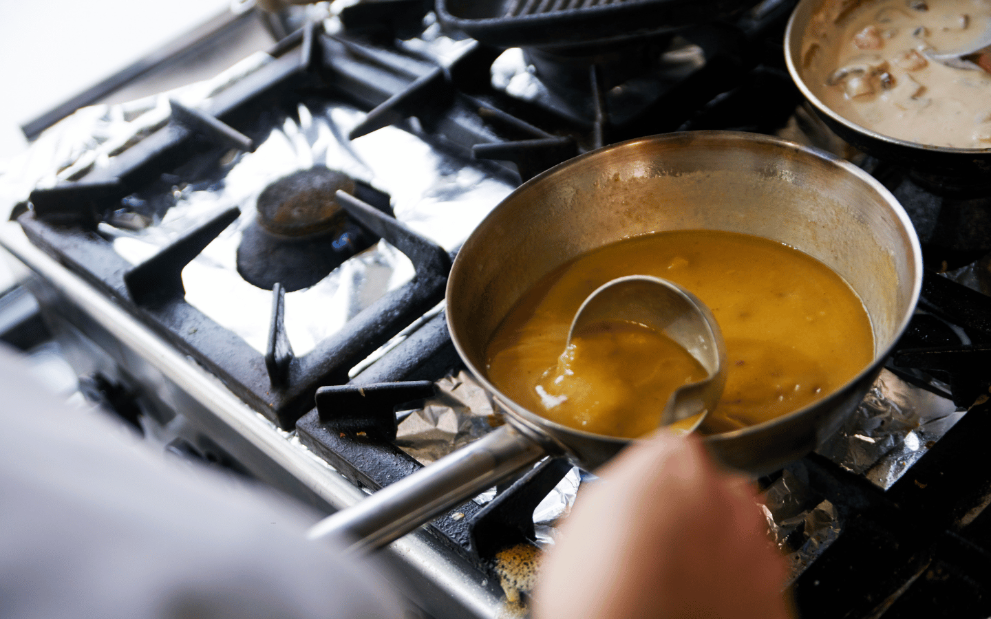 A person cooking gravy on a stovetop.