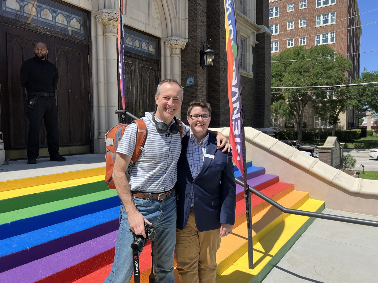 A photo of a female couple waving pride flags at a Pride celebration.