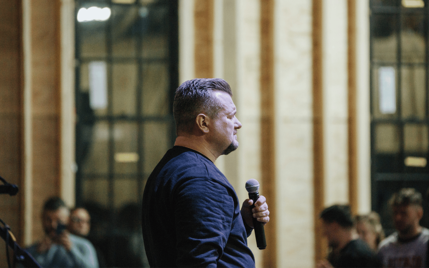 A male preacher holds a microphone.
