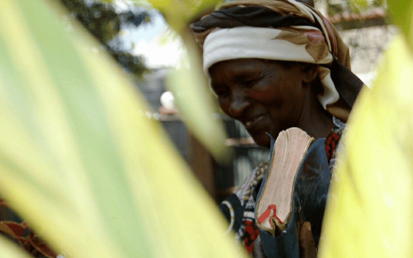 An older Kenyan woman prays with a Bible in her hand.