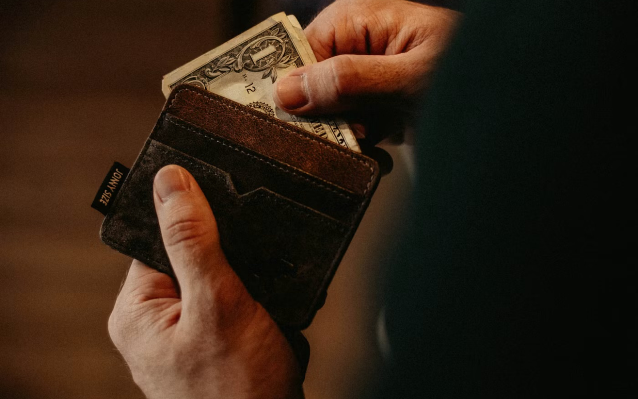 A man holding a wallet and removing money from it.