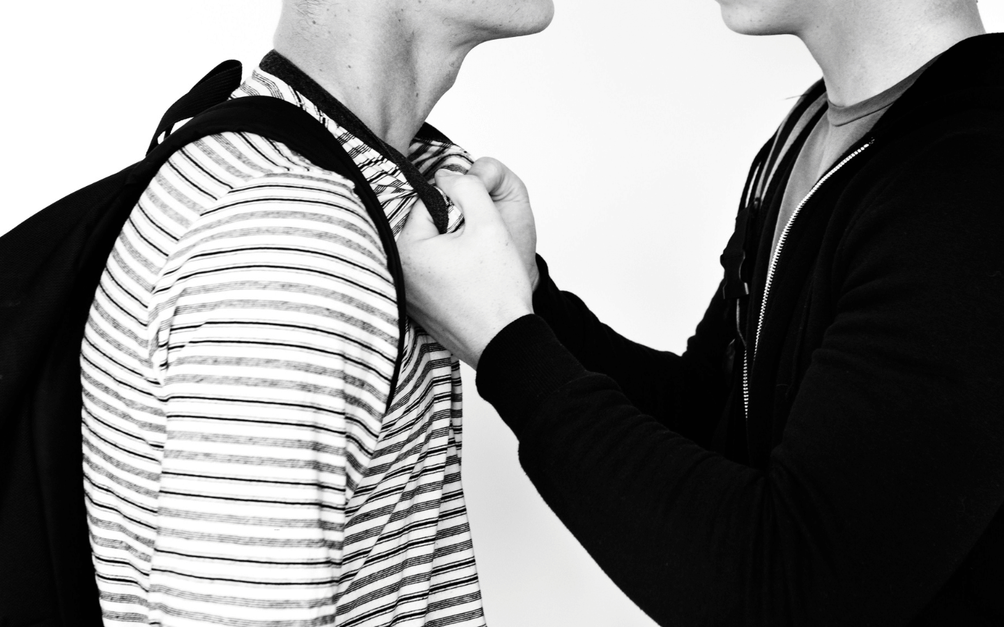 A bully grabs the shirt of a kid.