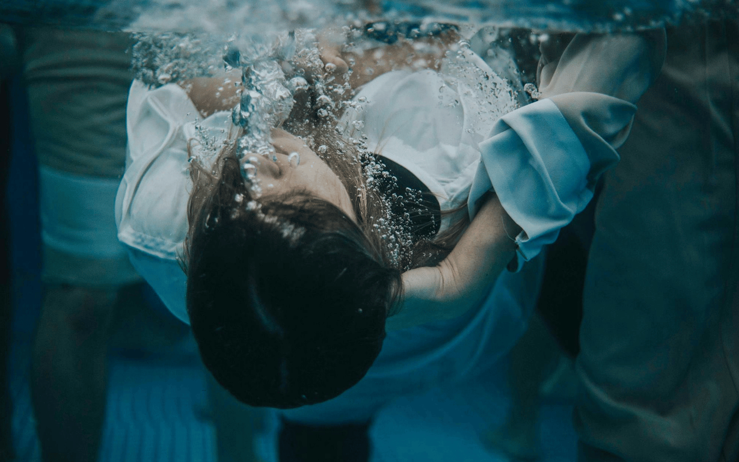 An underwater photo of a teenage girl being baptized.