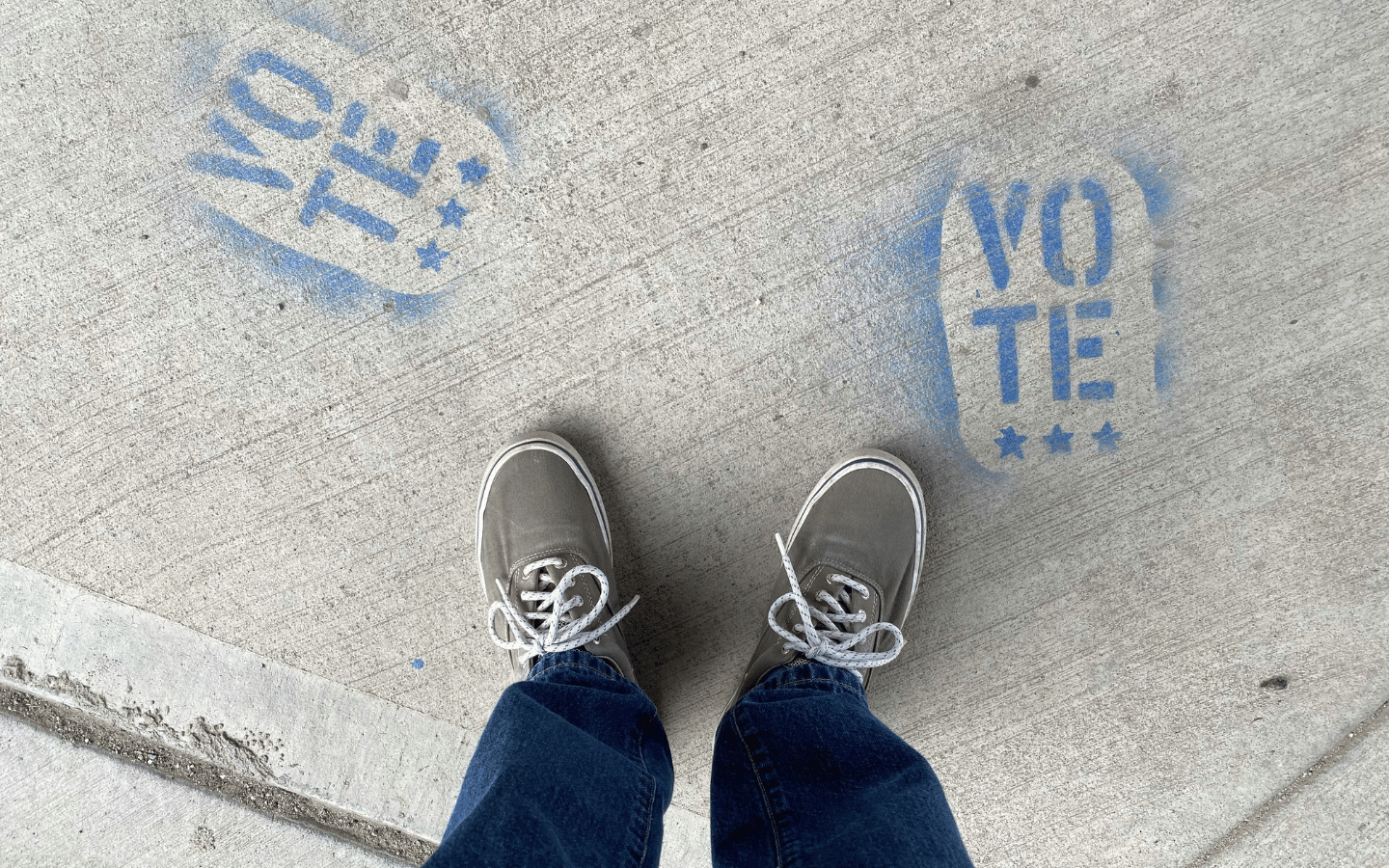 A person stands on concrete with the word “Vote” stamped on the floor.