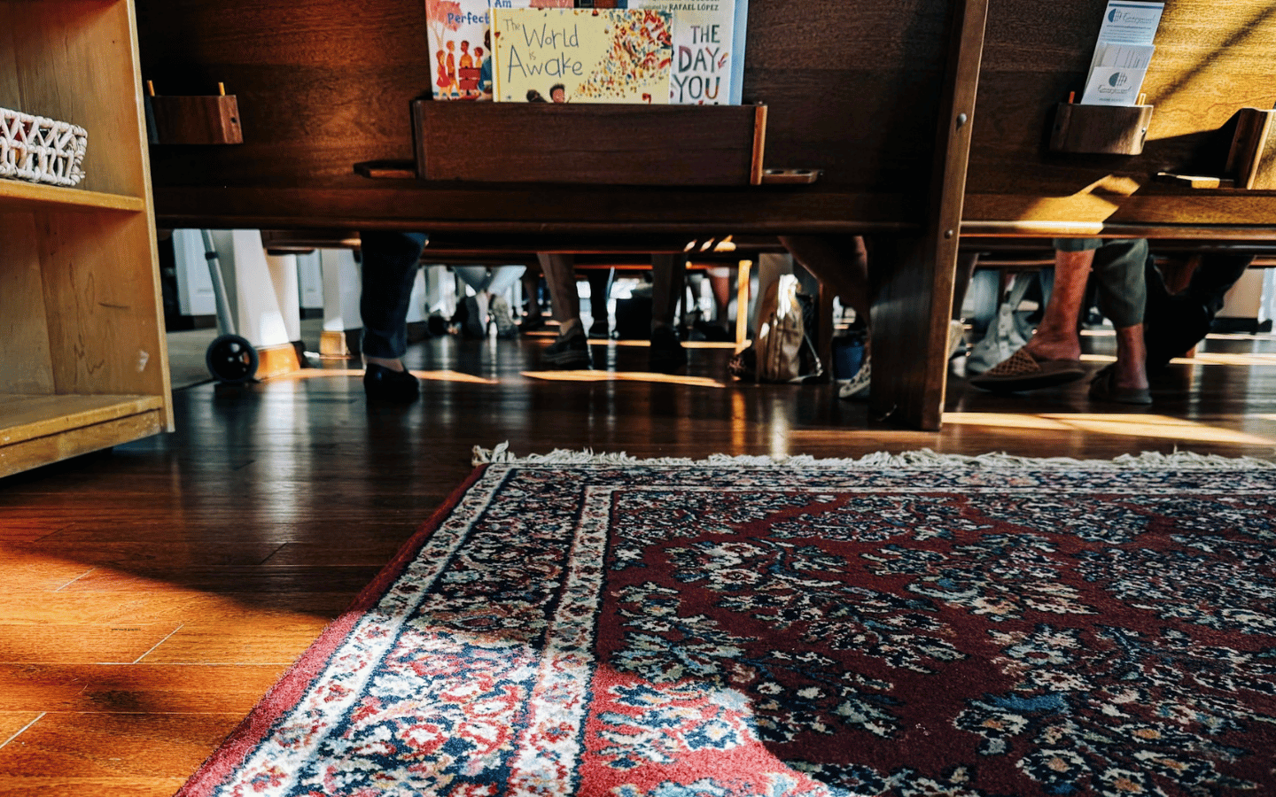 A photo from the floor of a sanctuary, looking forward on the feet of people in the pews.