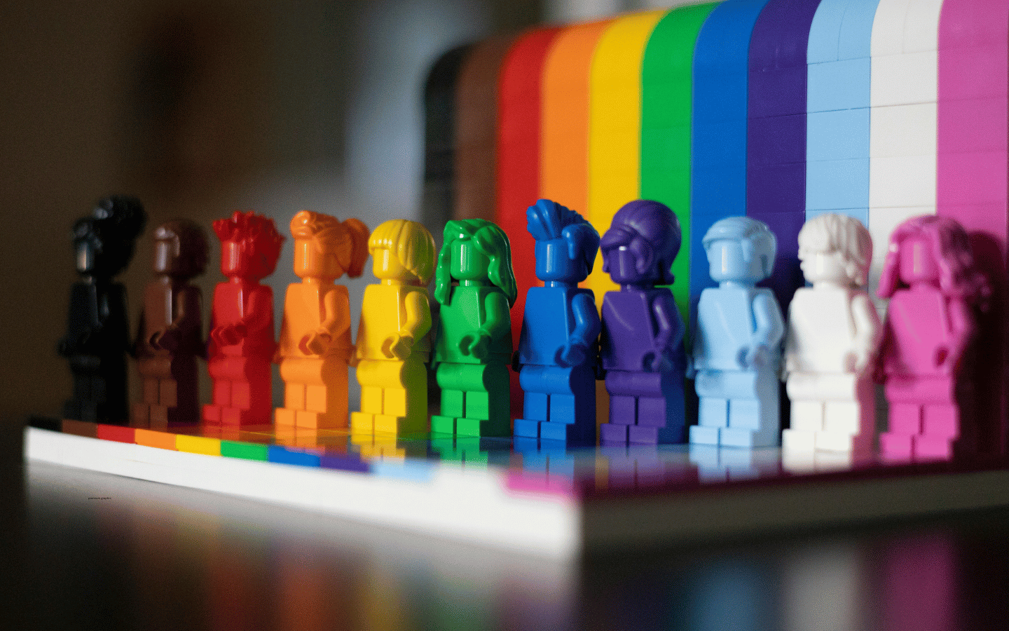 Toy figurines of people in every color of the trans-inclusive Pride flag.